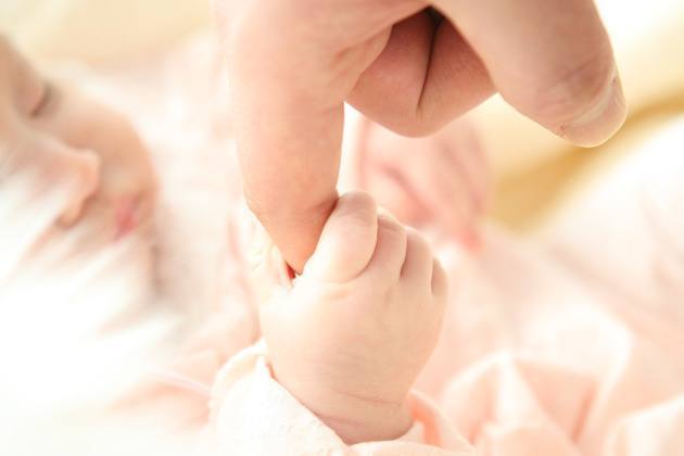 main de bébé qui tient un doigt
